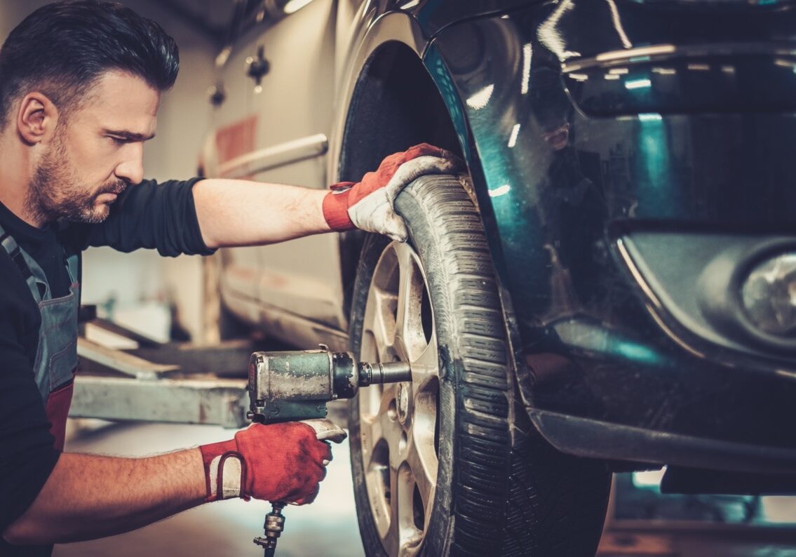 Professional car mechanic changing car wheel in auto repair service.